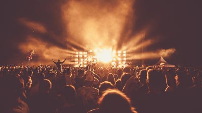 concert现场观众佩戴音乐耳塞的特写，霓虹蓝光背景下的听力保护意识展示